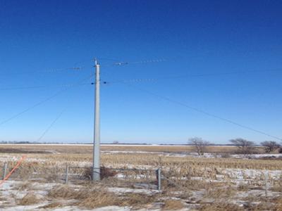 Steel utility pole on open plains with blue sky background